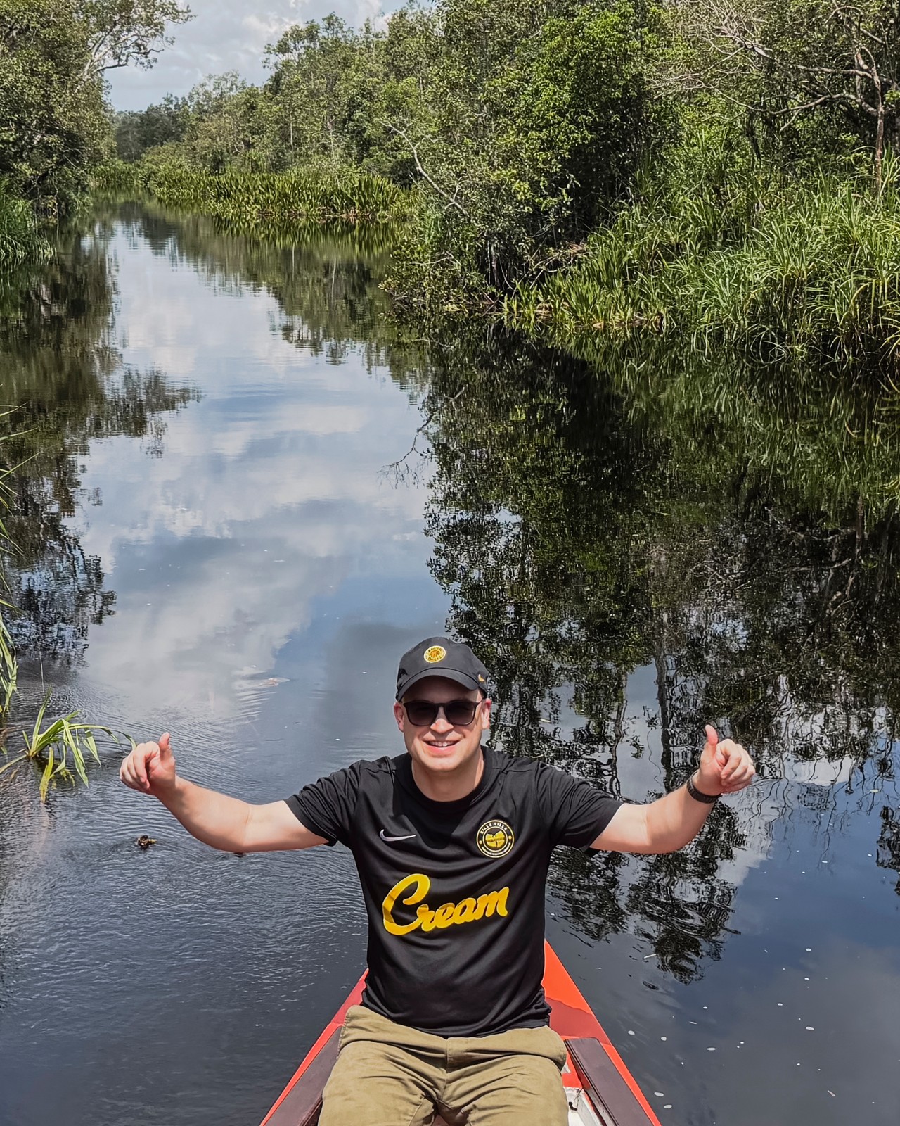 Dylan van Wetten seated in a boat on a tree-lined waterway.