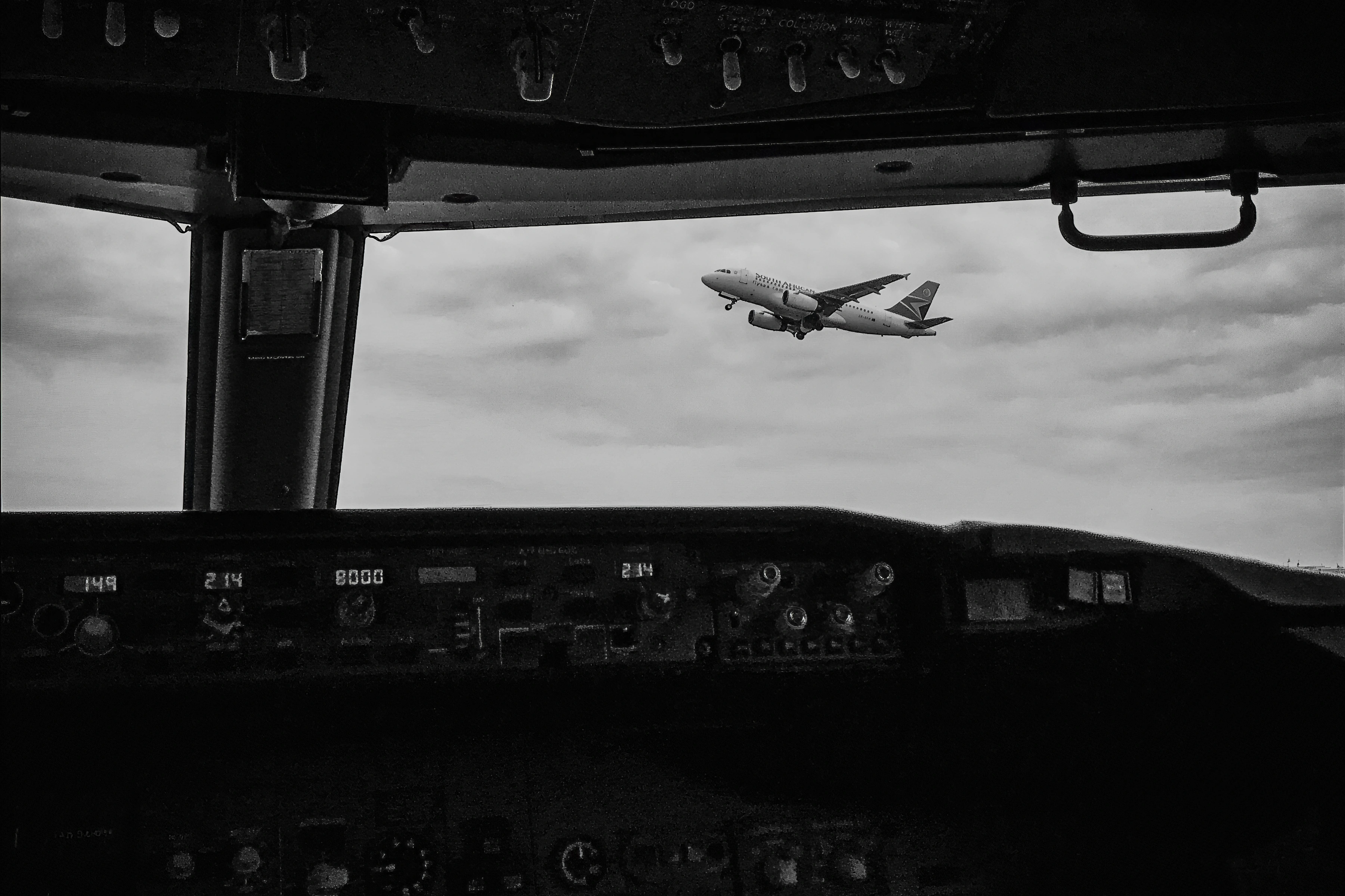 An airliner seen through cockpit glazing and instrument framing.