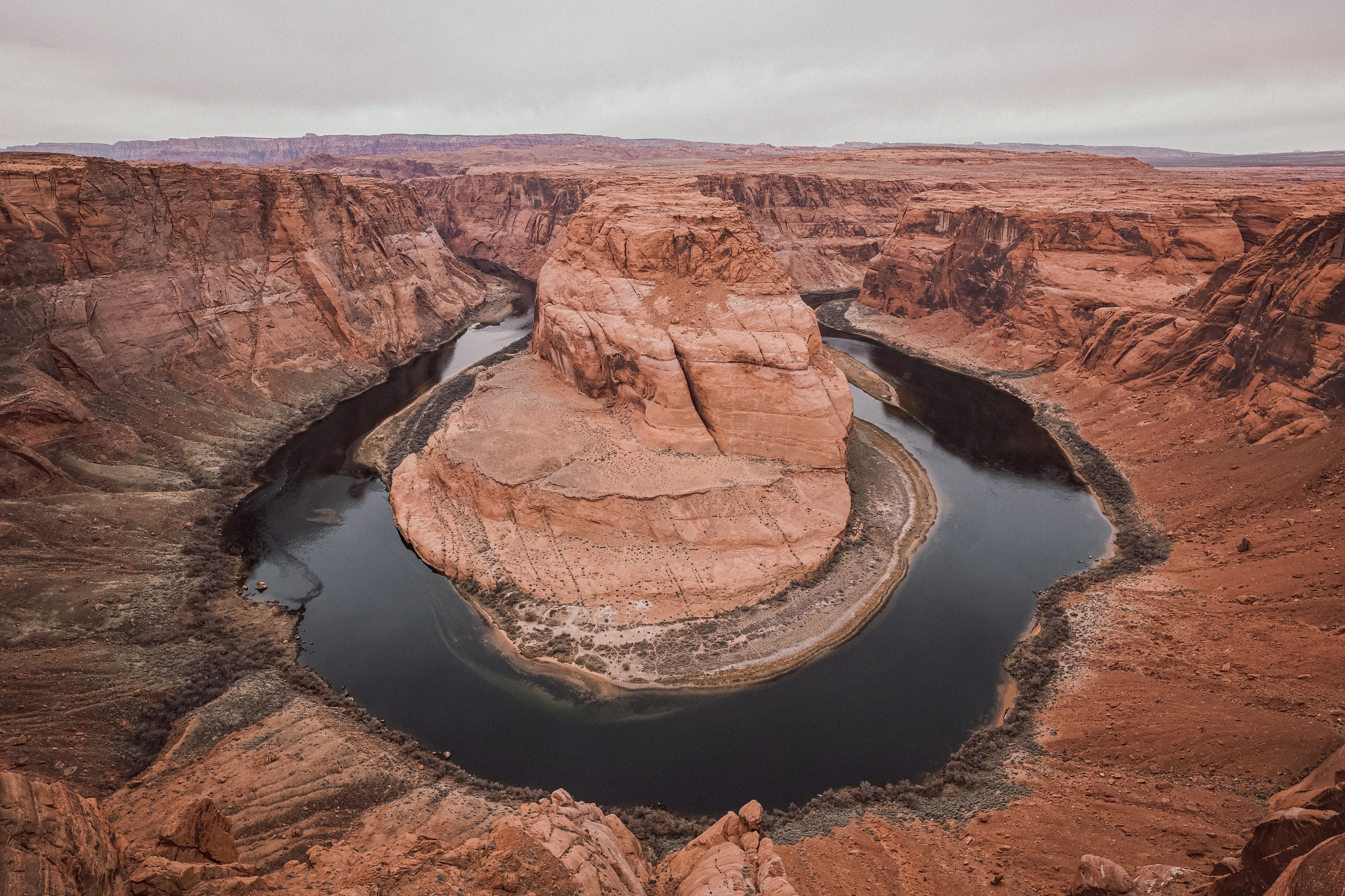 A broad river bend encloses a massive orange sandstone formation.